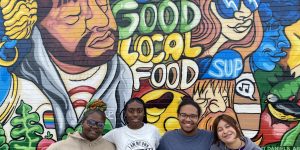 ThrYve YLT Members posing for a picture in front of a mural.