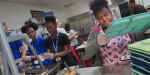 Image of young Black women working in an industrial kitchen.